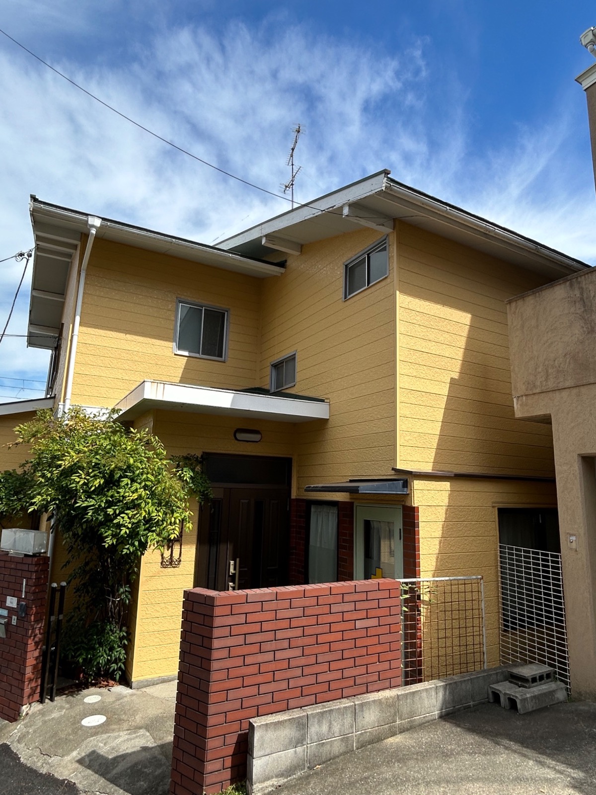 青空の下に建つ古着部屋のある黄色い家